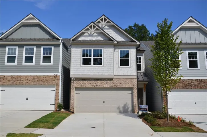 Two-story exterior with brick and siding facade, covered entry, and attached garage