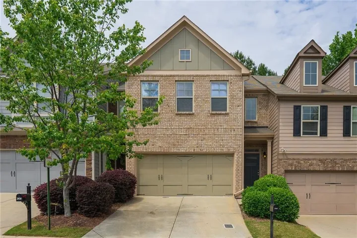 Brick and siding exterior with a two-car garage, covered entry, and mature landscaping