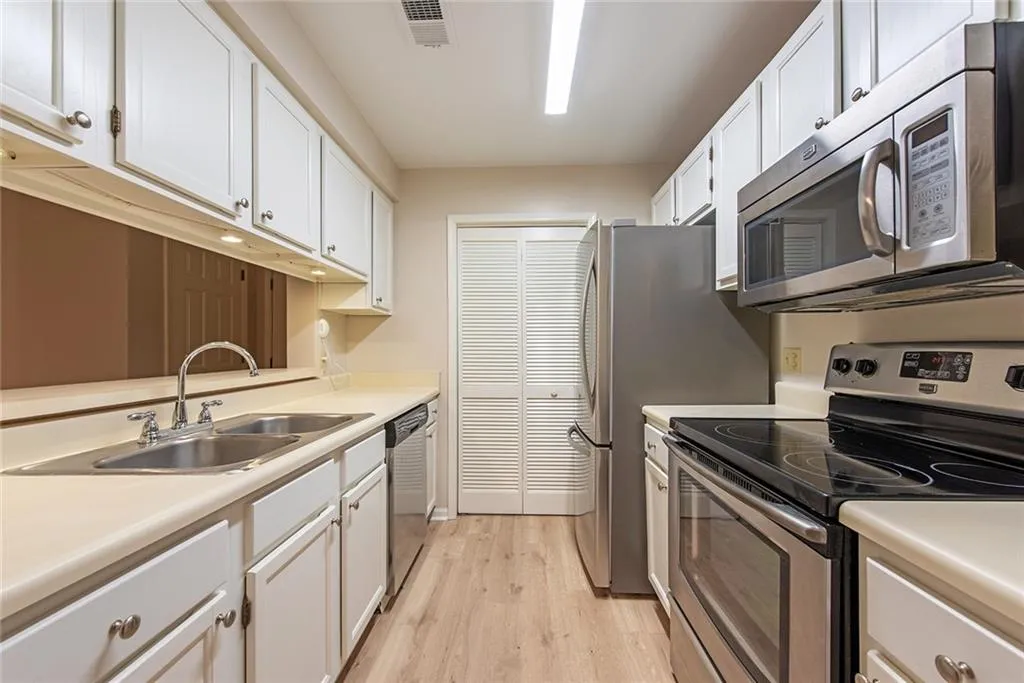 Kitchen with wood style floors, sink, stainless steel appliances, and white cabinets!