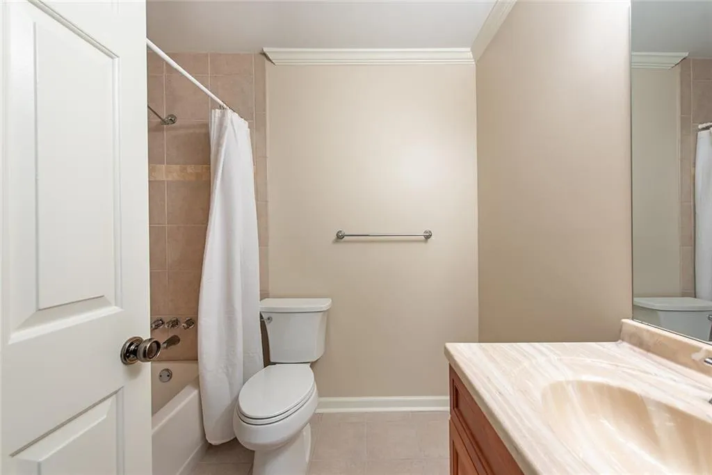 Full bathroom with vanity, shower / bath combo, tile patterned floors, crown molding, and toilet