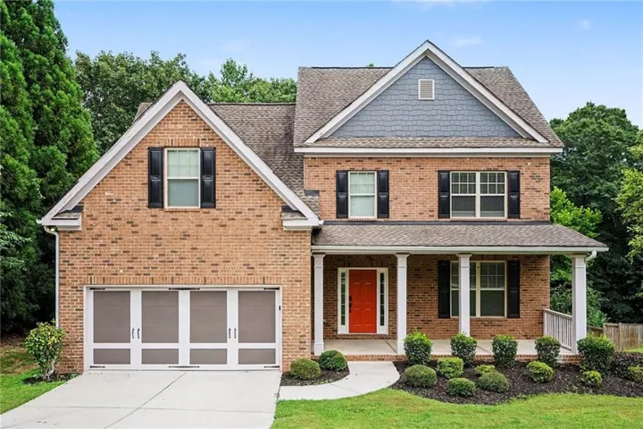 Brick facade home featuring a prominent red entry door and a covered front porch