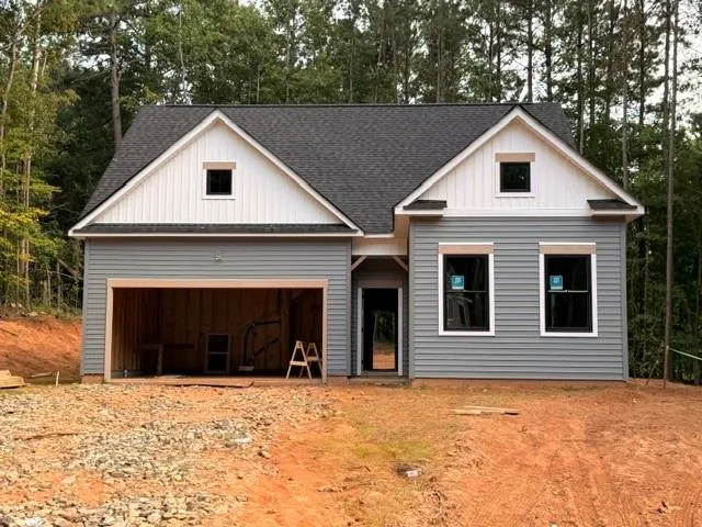 Gable roofline, light gray siding, white vertical siding accents, dark-framed windows, and an unfinished garage