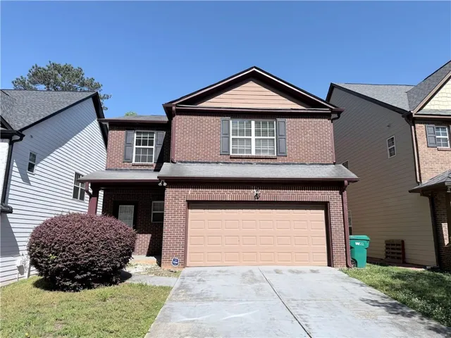 Two-story brick and siding construction featuring a prominent two-car garage with a panel door