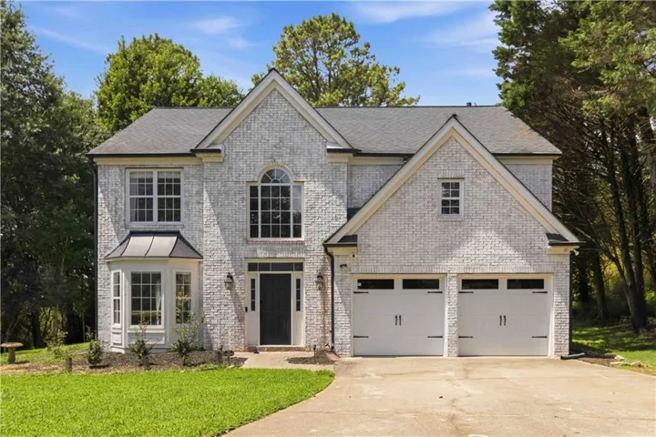 Brick exterior with gabled roof lines, featuring a bay window, arched window, and a two-car garage
