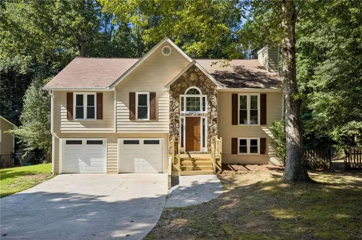 Split-level residence featuring a stone facade entry, a prominent arched window, and a two-car garage with individual doors