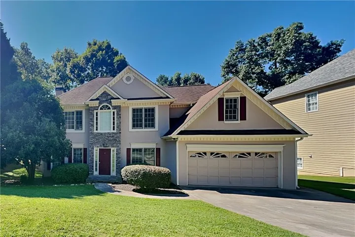 Two-story residence featuring a stone facade accent, arched transom window, and a two-car garage