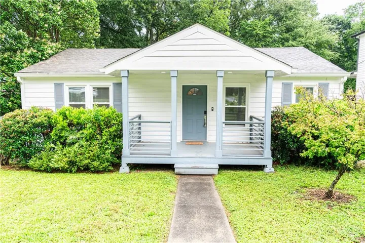 Inviting single-story residence featuring a covered front porch with blue-grey columns and railings