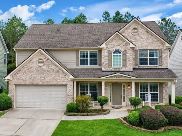 Two-story residence featuring a brick and siding facade, covered front porch, and a two-car garage