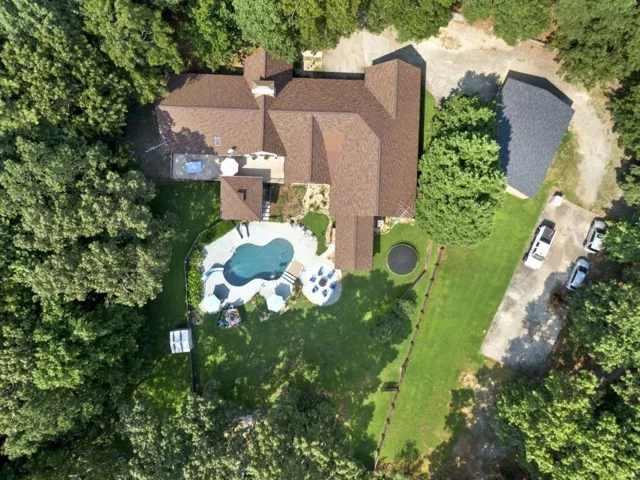 Expansive property featuring a freeform pool, surrounding concrete patio, and a large grassy area