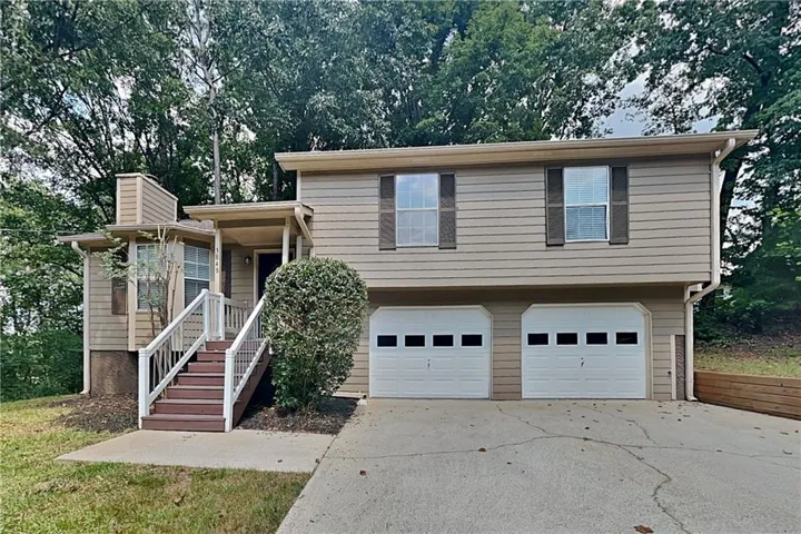 Split-level residence featuring tan siding and a two-car garage