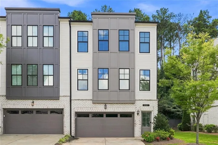 Three-story facade featuring white brick, horizontal siding, and grey paneling