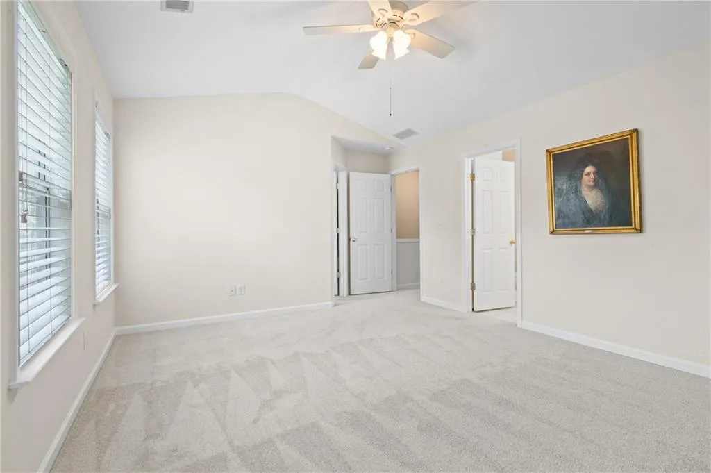 Unfurnished bedroom with carpet floors, lofted ceiling, and a ceiling fan