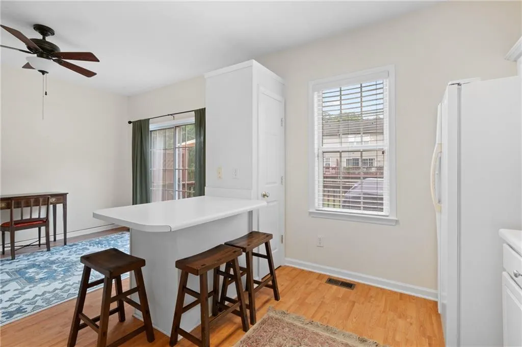 Kitchen with freestanding refrigerator, light wood-type flooring, ceiling fan, a kitchen bar, and a peninsula