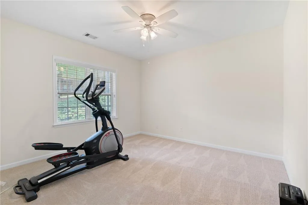Workout room featuring light carpet and ceiling fan