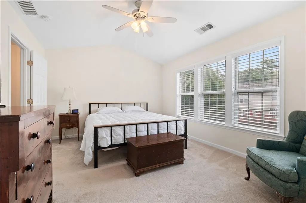 Bedroom with vaulted ceiling, light colored carpet, and ceiling fan