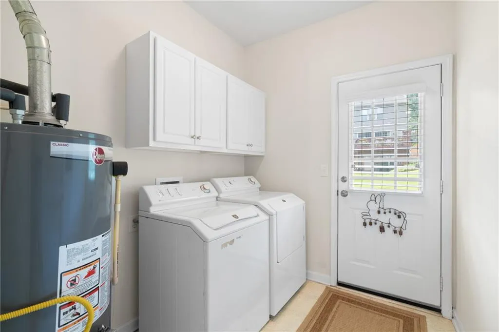 Washroom with washing machine and dryer, water heater, and cabinet space