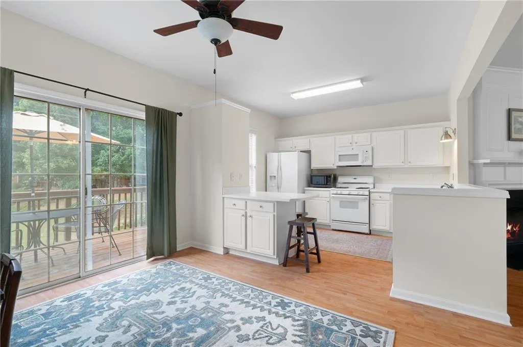 Kitchen with a peninsula, white appliances, ceiling fan, and light wood finished floors