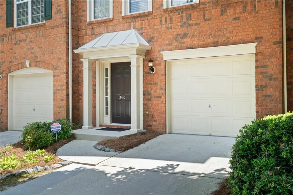 Entrance to property with brick siding, an attached garage, and driveway