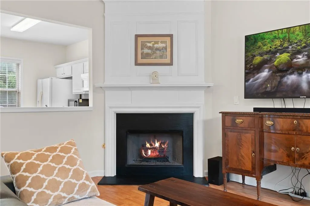 Living area with light wood-style floors and a warm lit fireplace