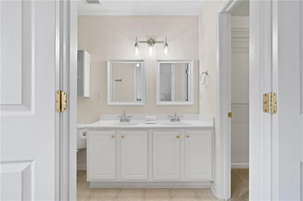 Full bath featuring double vanity and baseboards