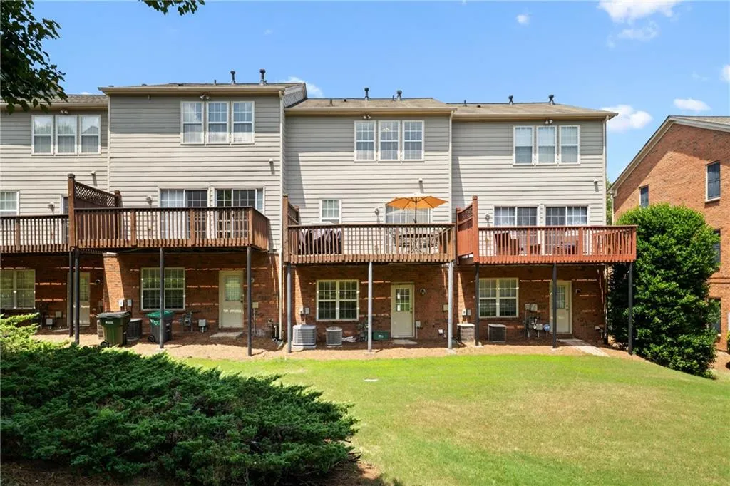 Rear view of house with brick siding, a lawn, and a deck