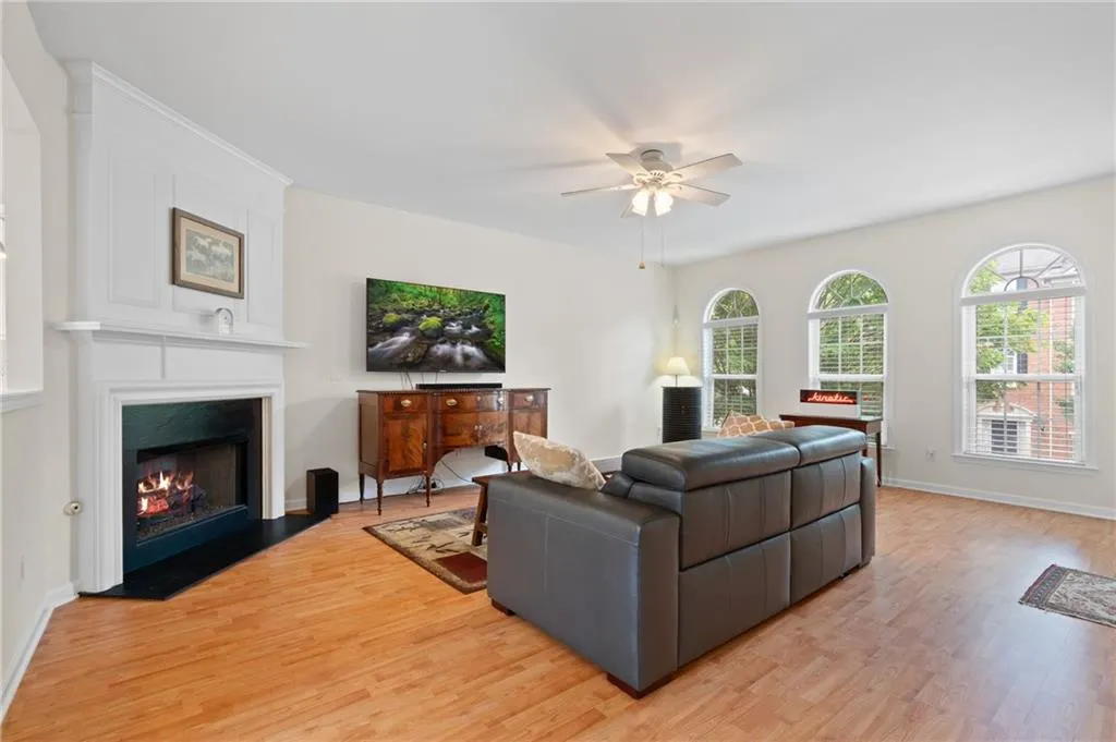 Living room with a ceiling fan, a fireplace with flush hearth, and light wood-type flooring