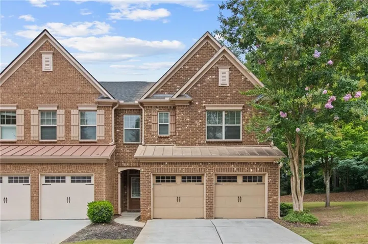 Brick exterior with multiple gables, individual garage doors, and decorative window shutters