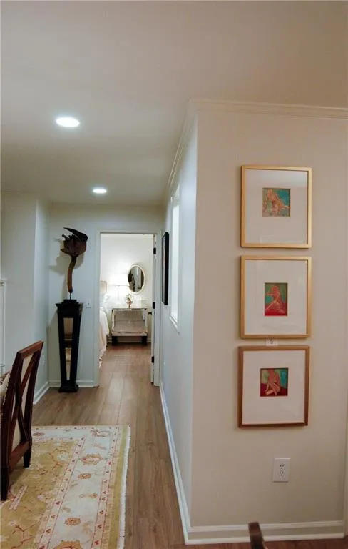 Corridor with ornamental molding and light hardwood / wood-style floors