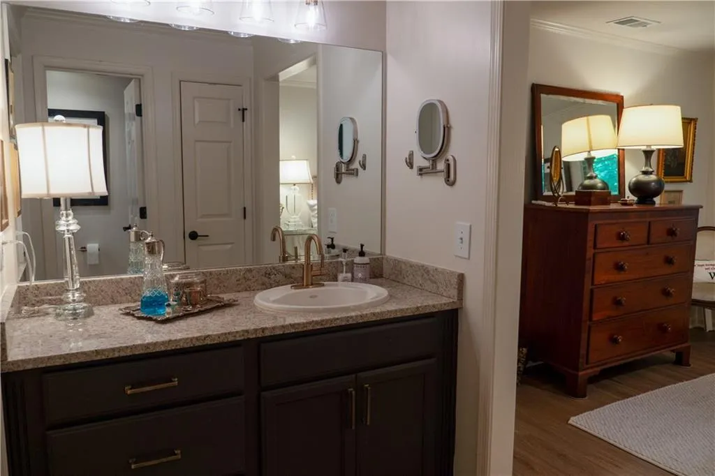 Primary Bathroom featuring vanity, ornamental molding, and wood-type flooring