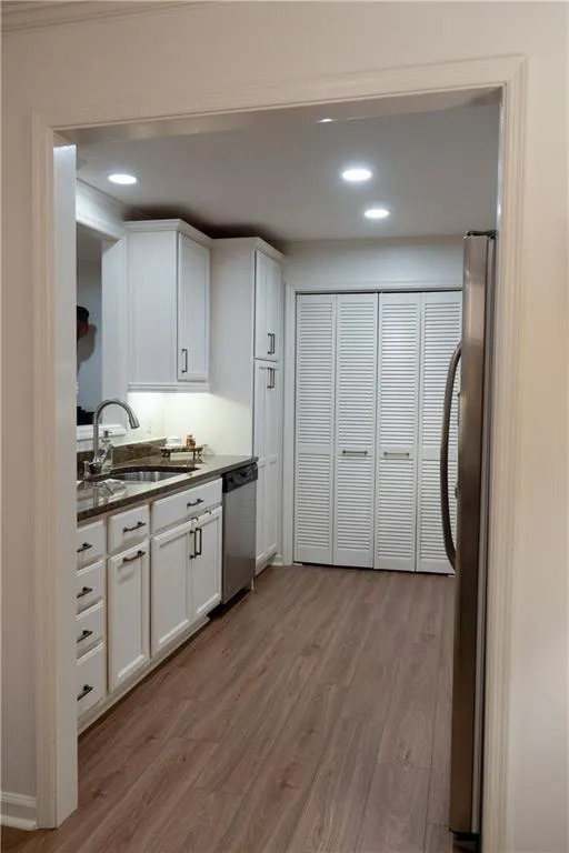 Kitchen featuring sink, appliances with stainless steel finishes, light wood-type flooring, and white cabinets