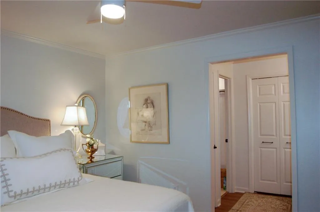 Bedroom featuring crown molding, hardwood / wood-style flooring, ceiling fan, and a closet