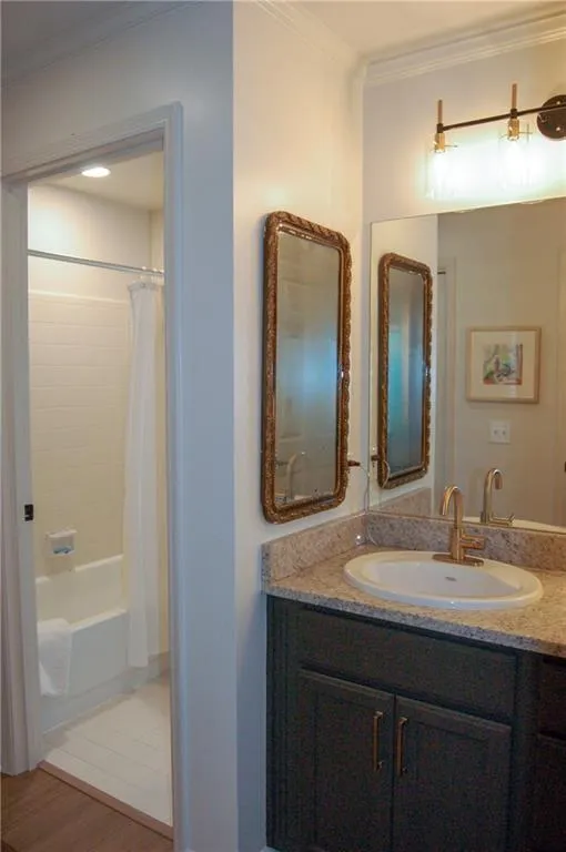 Bathroom with wood-type flooring, shower / tub combo, crown molding, and vanity
