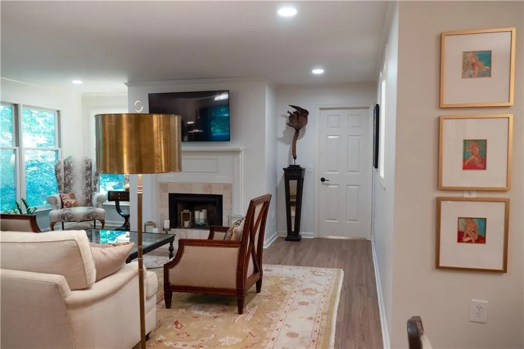 Living room with a tiled fireplace, ornamental molding, and hardwood / wood-style floors