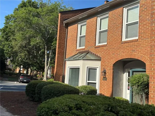 Brick exterior featuring an arched entryway, a bay window with a copper-finish roof, and white-framed windows