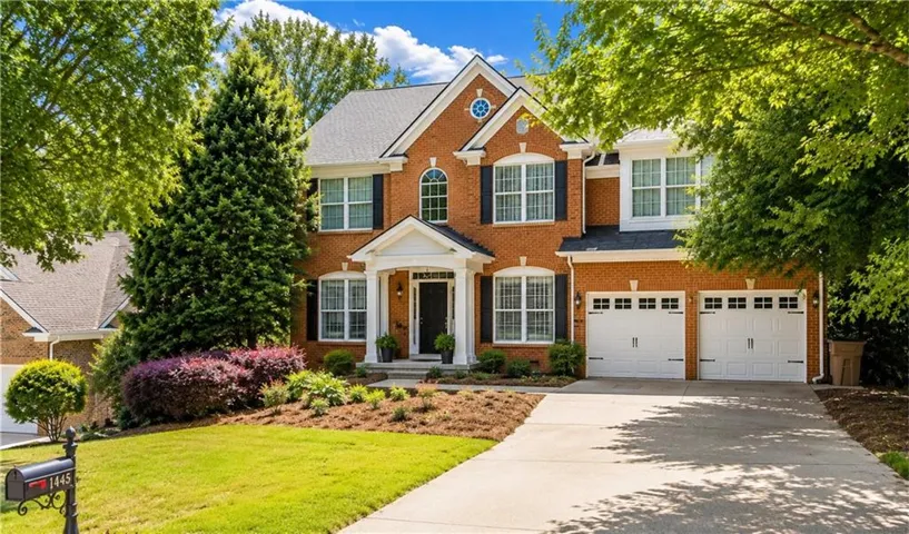 A timeless brick traditional home with classic curb appeal, featuring a welcoming covered front entry.