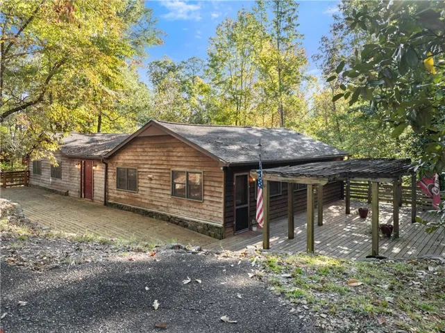 View of side of property featuring a wooden deck and a shingled roof