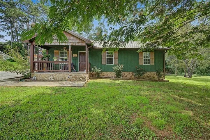 Green-sided residence featuring a covered front porch with wood railings and stone accents