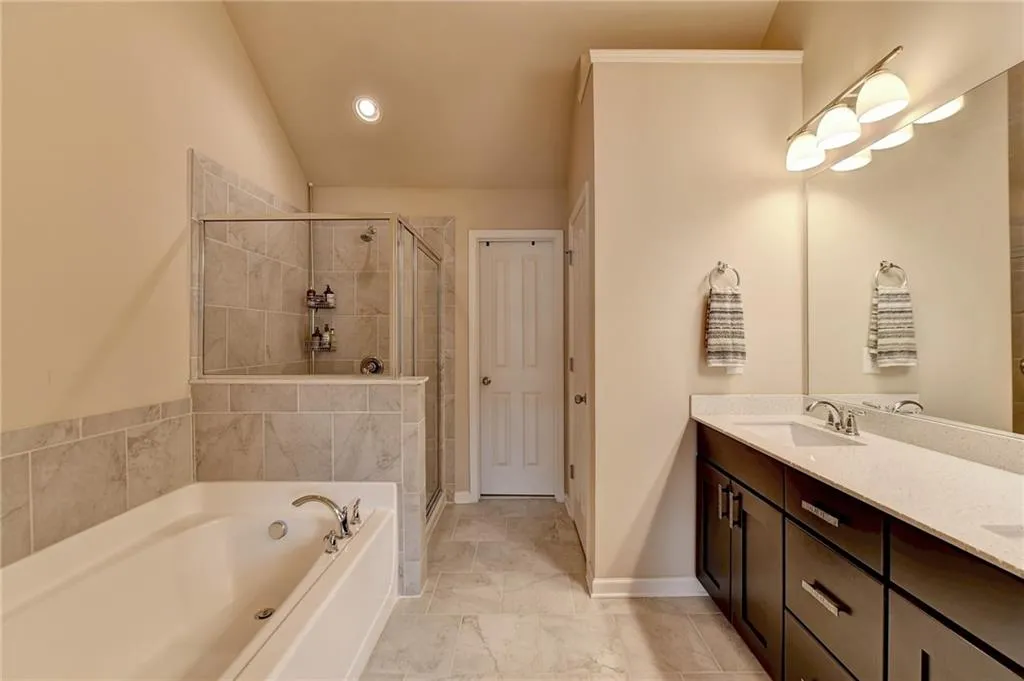 Bathroom with lofted ceiling, double sink vanity, tile floors, and separate shower and tub