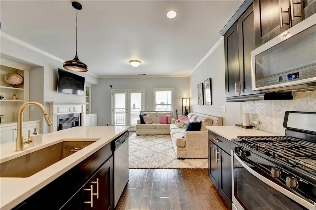 Kitchen featuring sink, decorative light fixtures, dark hardwood / wood-style flooring, ornamental molding, and appliances with stainless steel finishes