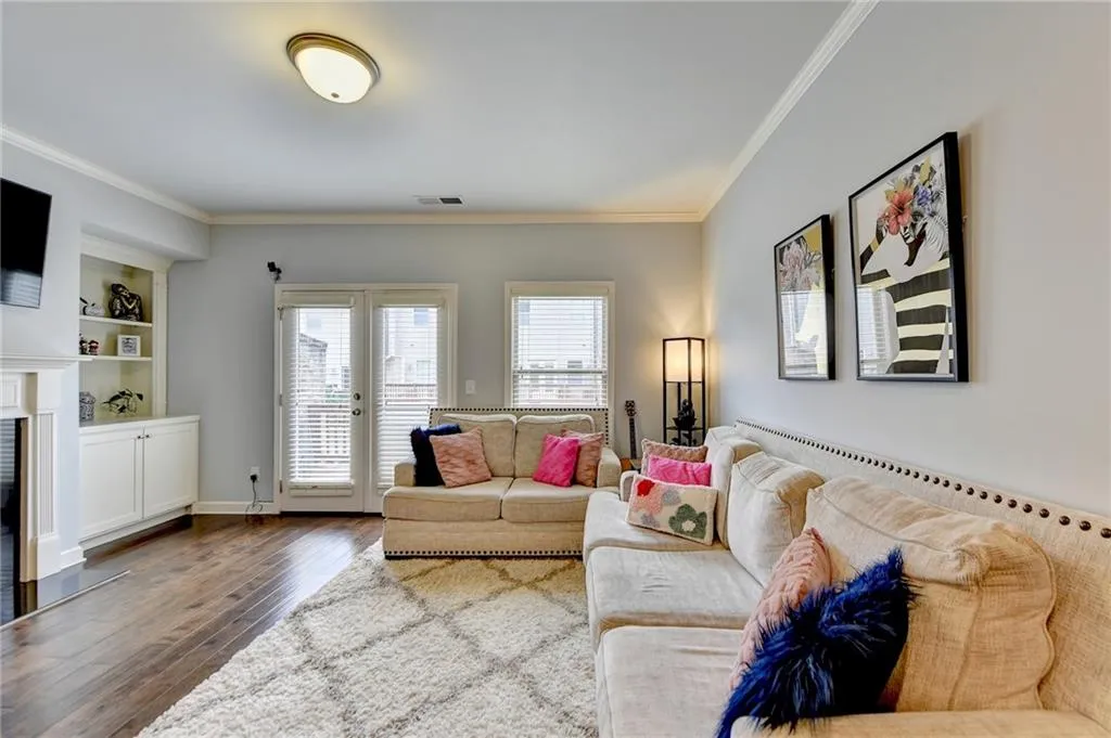 Living room with ornamental molding, hardwood / wood-style flooring, built in features, and french doors