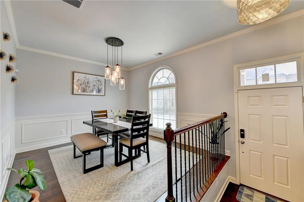 Dining area with dark hardwood / wood-style floors, ornamental molding, and an inviting chandelier