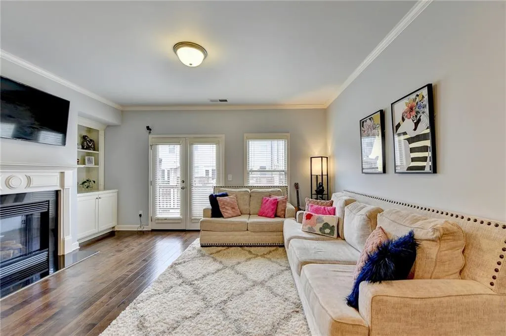Living room with wood-type flooring, built in features, french doors, and ornamental molding