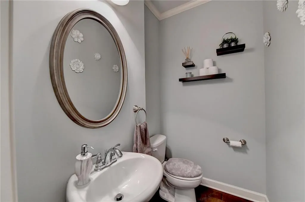 Bathroom featuring toilet, sink, and crown molding