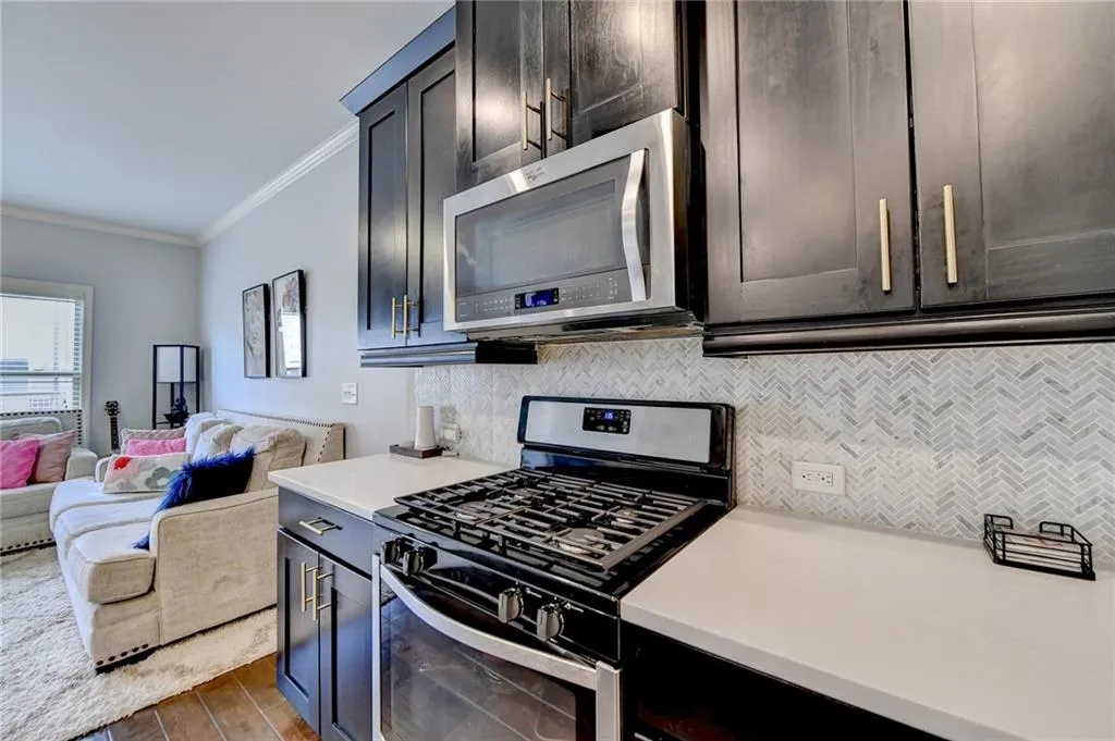 Kitchen with dark hardwood / wood-style floors, appliances with stainless steel finishes, crown molding, and backsplash