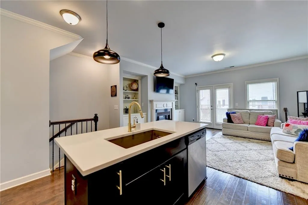 Kitchen featuring sink, dark hardwood / wood-style floors, a kitchen island with sink, dishwasher, and pendant lighting