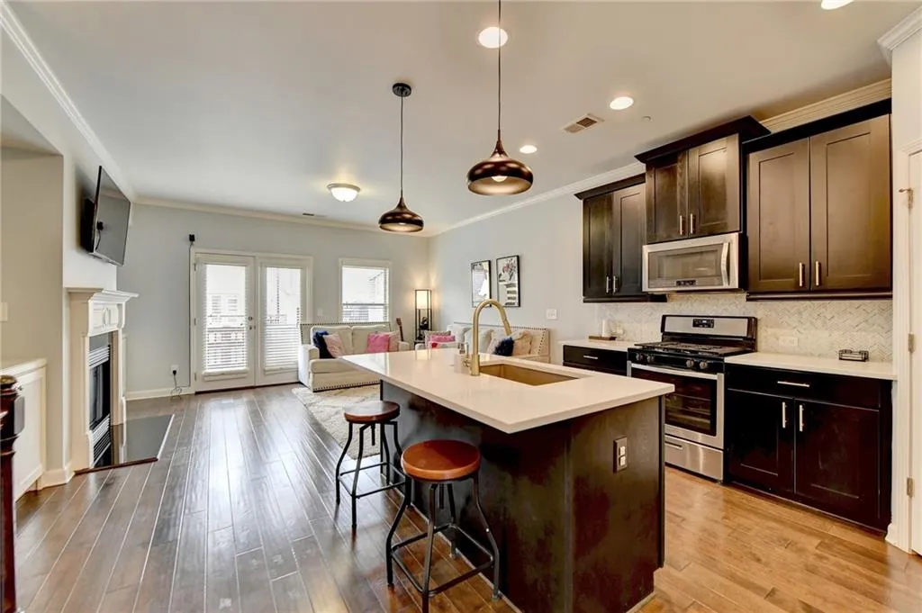 Kitchen with backsplash, stainless steel appliances, sink, light wood-type flooring, and decorative light fixtures