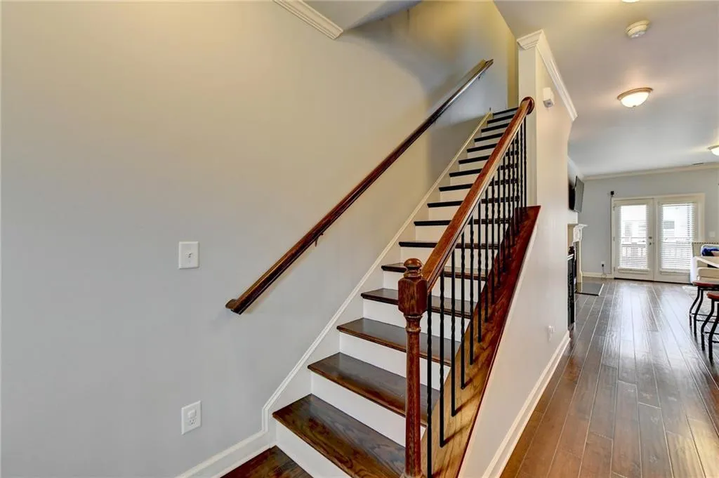 Staircase with french doors, crown molding, and dark wood-type flooring