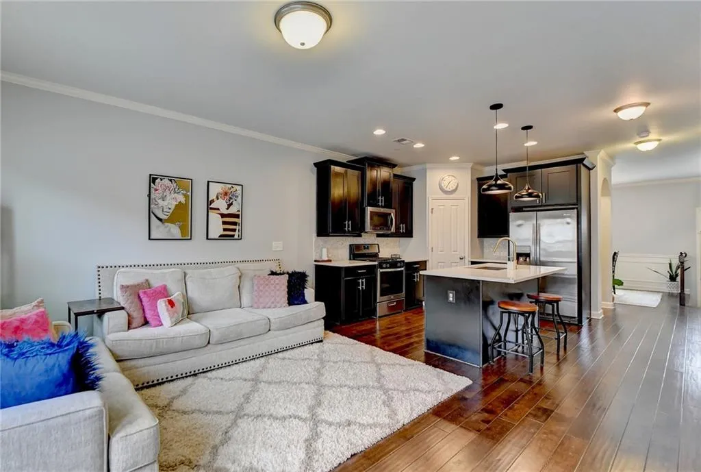 Living room featuring dark hardwood / wood-style floors, sink, and crown molding