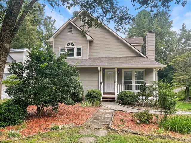 Two-story residence featuring light gray siding, a covered front porch with white railings, and a prominent front door with decorative glass