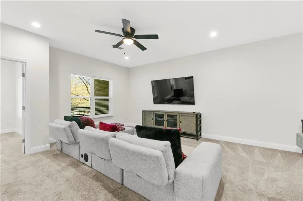 Living area featuring ceiling fan, light colored carpet, and recessed lighting